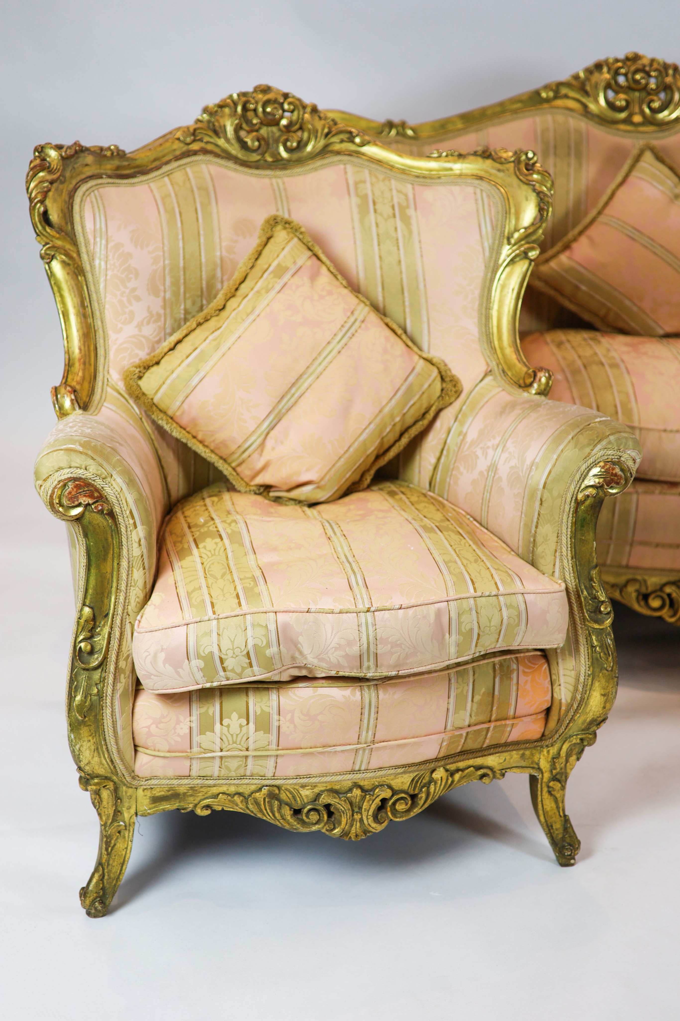 A Louis XV style carved gilt wood five piece suite, consisting of a three seater settee and four fauteuils, all with scroll carved backs and arms, on short cabriole legs